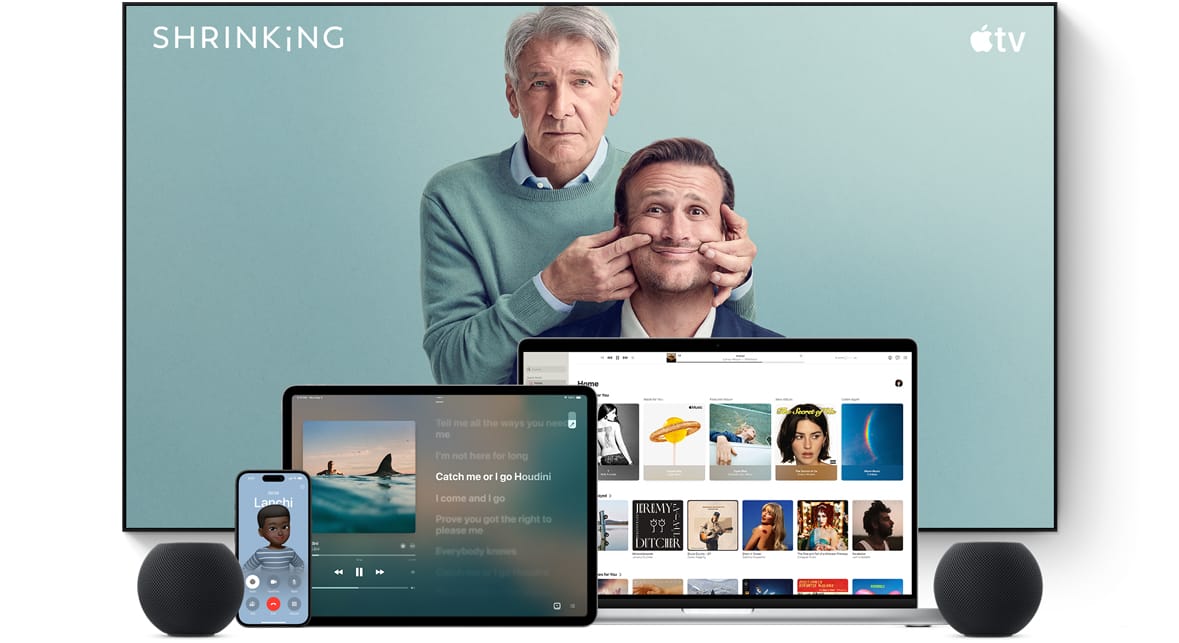 Large flat screen television showing two male characters from the Apple TV series Shrinking. A MacBook Pro, an iPad, an iPhone and a Midnight HomePod mini are arranged in front.