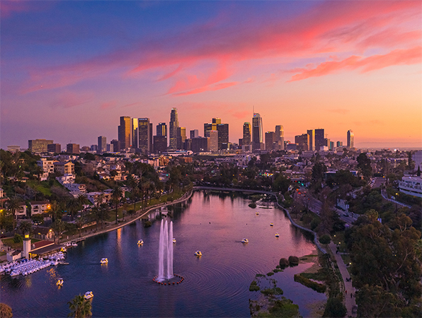 Imagen aérea muestra los rascacielos de Los Ángeles con un parque y un lago al frente.