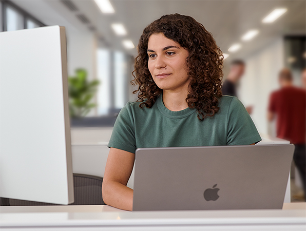 オフィスでMacBookとStudio Displayを使っているAppleのチームメンバー。