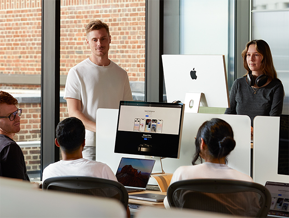 5人のApple社員がデスクに集まり会話をしている。