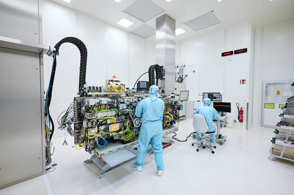 Due tecnici in indumenti protettivi accanto a un grande macchinario, in un ambiente simile a un laboratorio nello stabilimento TRUMPF a Ditzingen.