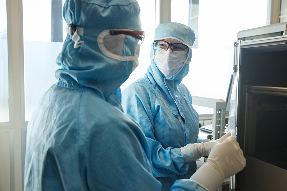 Due tecnici in indumenti protettivi che si guardano in un ambiente simile a un laboratorio nello stabilimento TRUMPF di Ditzingen.