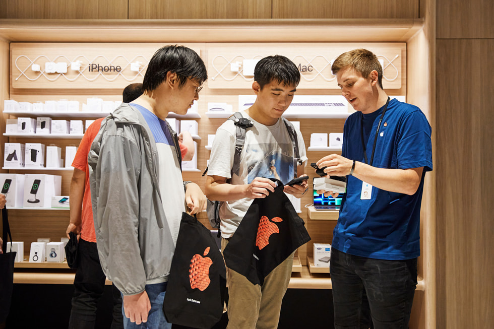 An Apple team member assisting customers with iPhone 14 at Apple Battersea.