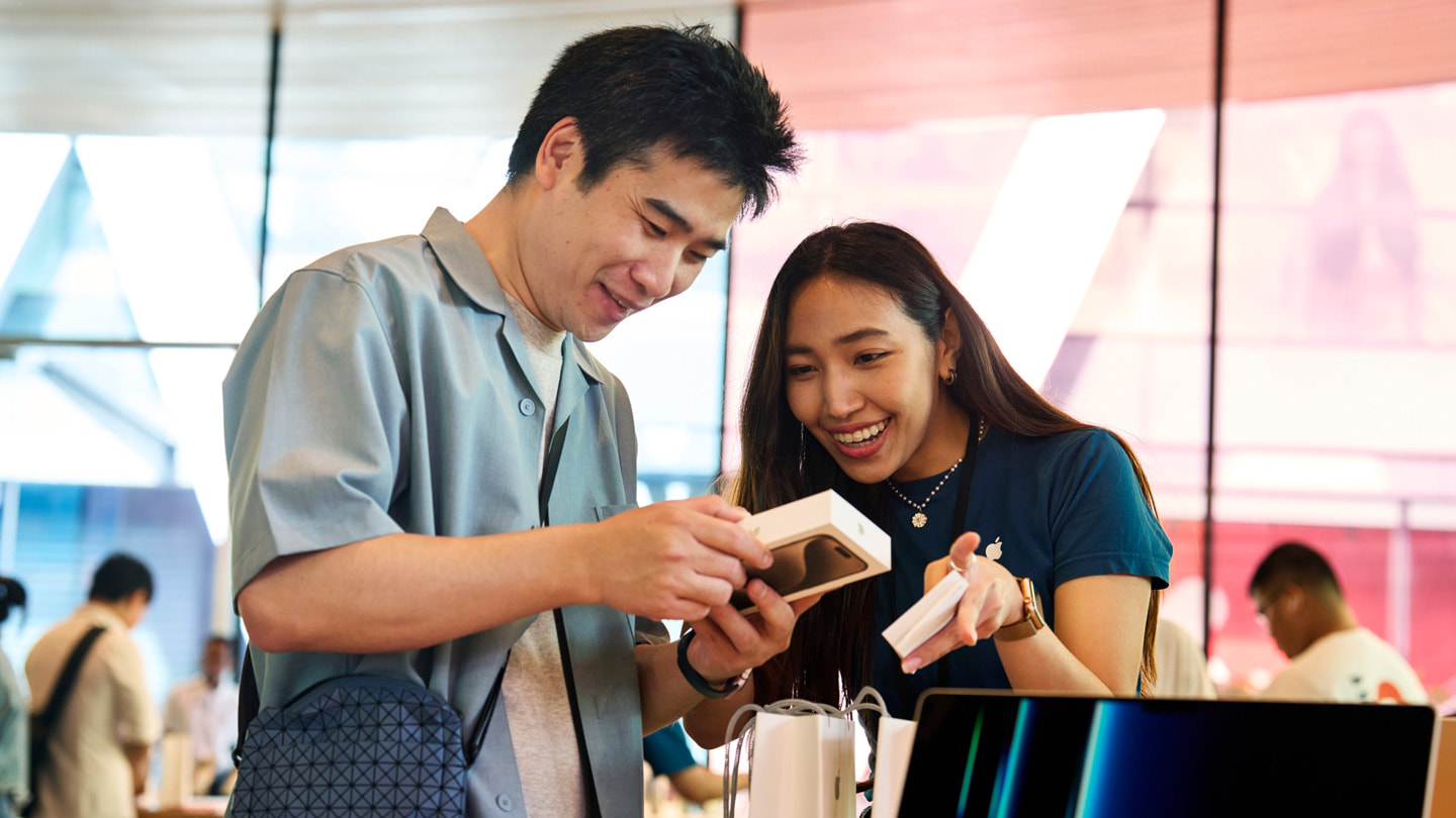 A customer unboxes their new iPhone 15 Pro with an Apple Central World team member’s assistance.
