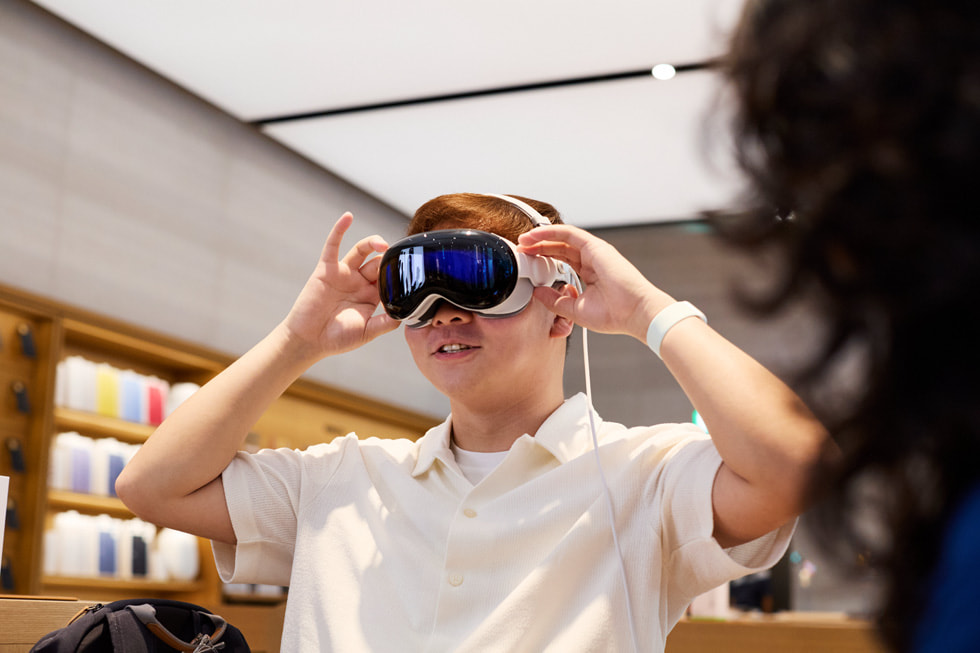 A customer wearing Apple Vision Pro holds both hands to the sides of his head.