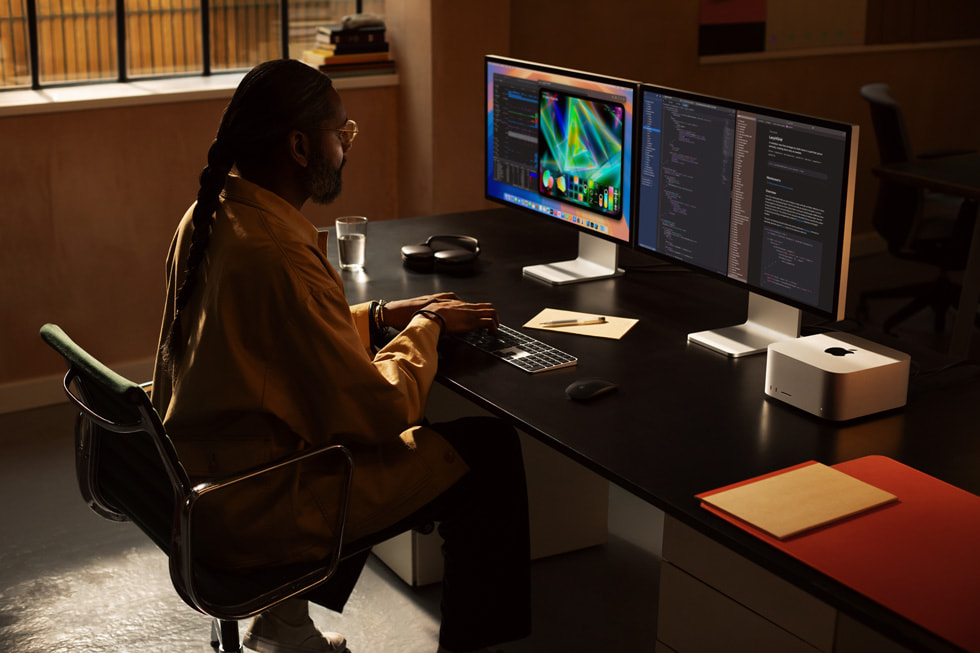 In an office-like setting, a creative works on two Mac Studio Display devices with Mac Studio.