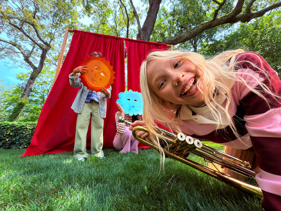 A photo taken with iPhone 17 features three children playing outside.