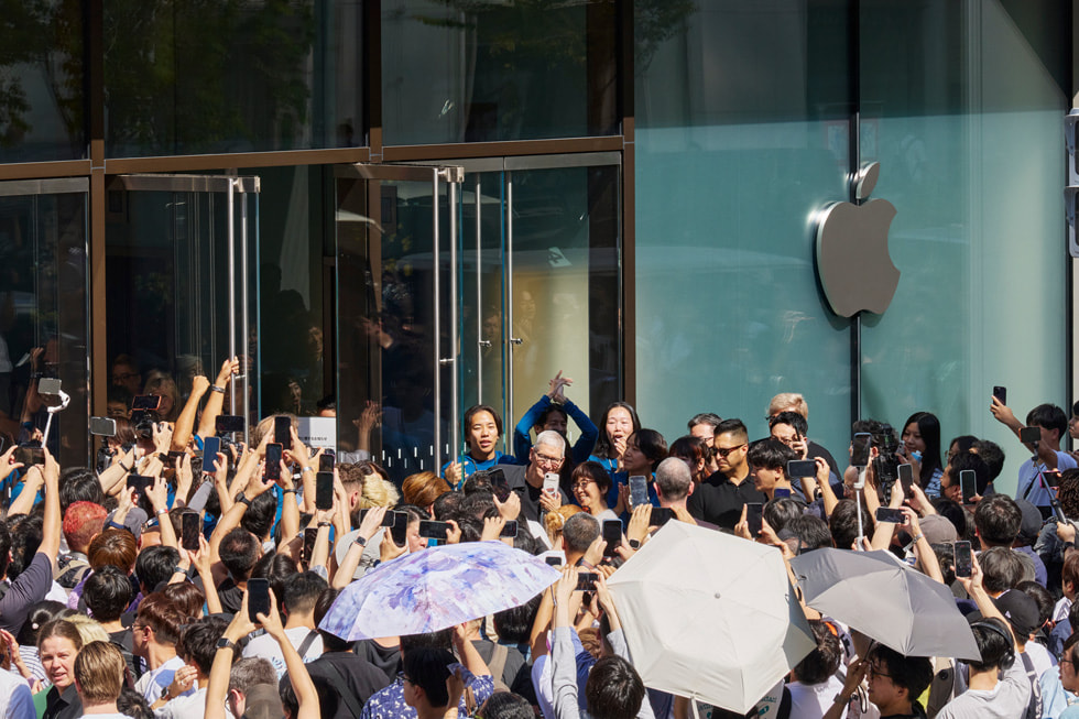 Tim Cook is surrounded by a crowd of customers and team members outside Apple Ginza.