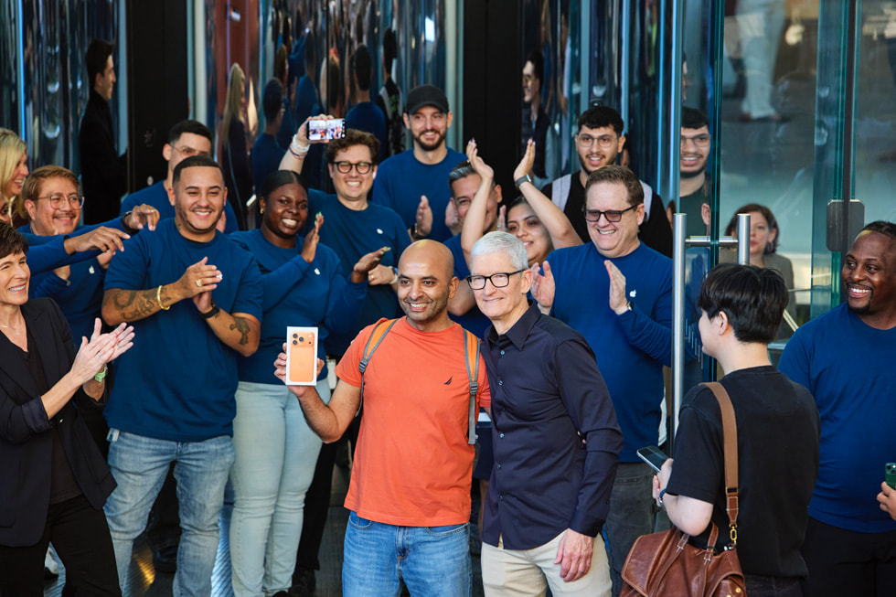 Tim Cook poses with a customer holding their new cosmic orange iPhone 17 Pro outside of Apple Fifth Avenue in New York.