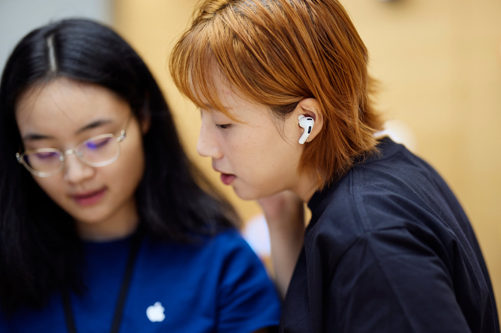 An Apple team member assists a customer in testing out AirPods Pro 3 at Apple Nanjing East in Shanghai.