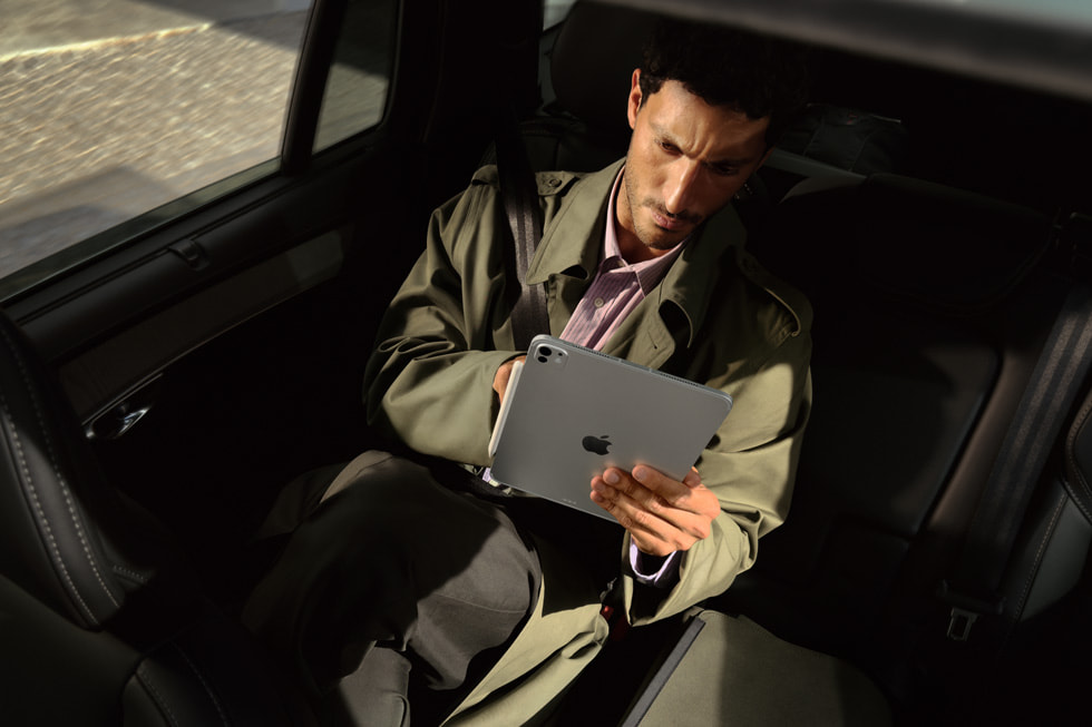 أحد الركاب في المقعد الخلفي لسيارة يستخدم جهاز iPad Pro الجديد بشريحة M5 أثناء التنقل.