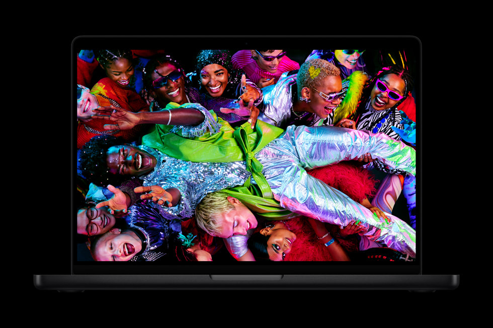 The display on MacBook Pro shows an image of people dressed in vibrant clothes.