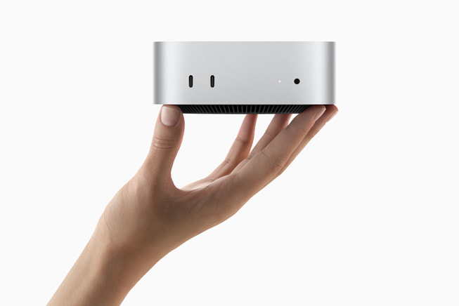 A hand holds up Mac mini.