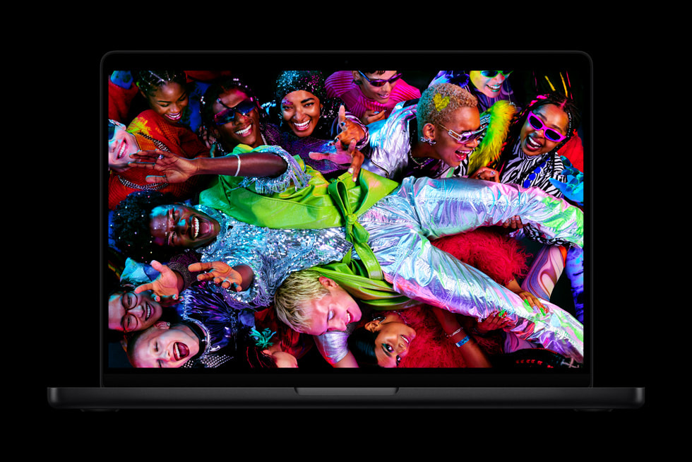 MacBook Pro shows a colorful screen with a crowd of people wearing vibrant clothes.