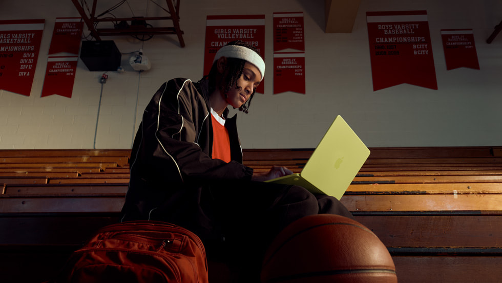 A person uses their silver MacBook Neo in an auditorium-like setting.