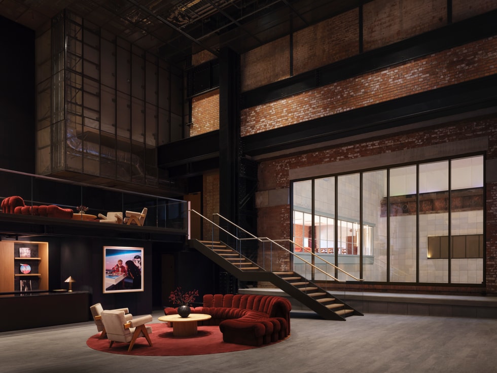 A comfortable foyer with a seating area, a large glass window and a staircase inside Apple Music Hall.