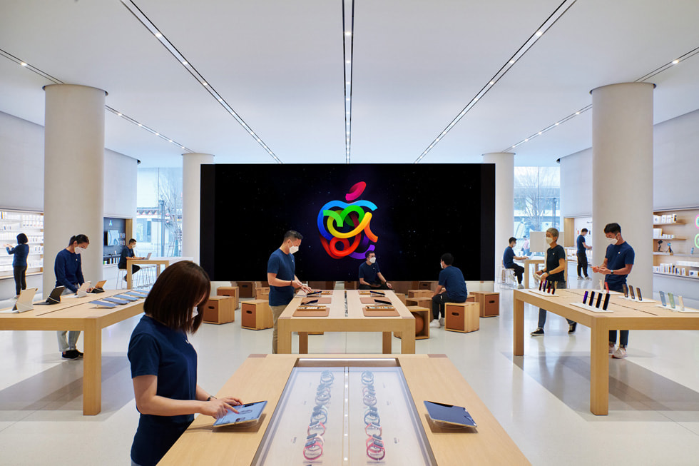 Freestanding video wall facing a number of display tables with Specialists around inside Apple Changsha.
