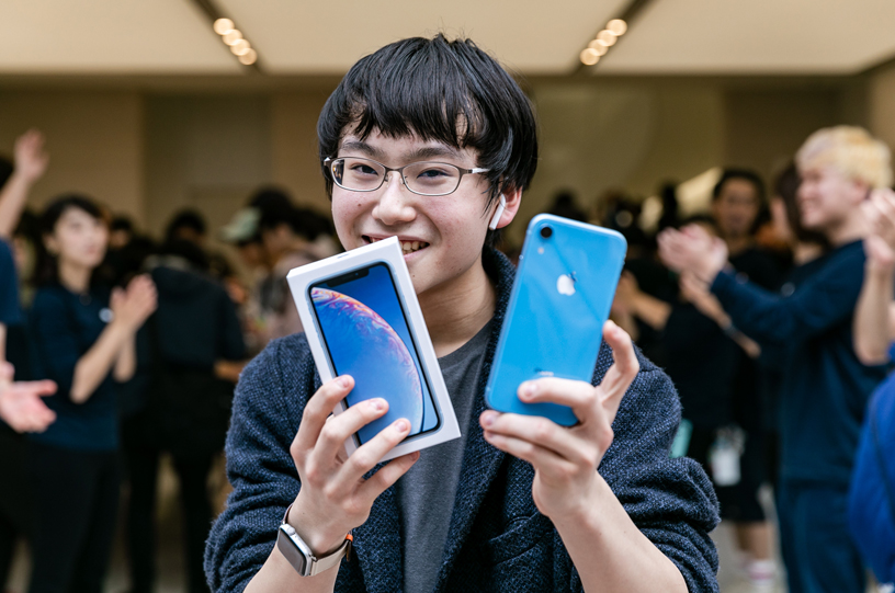 Customer holds up blue iPhone XR and box.