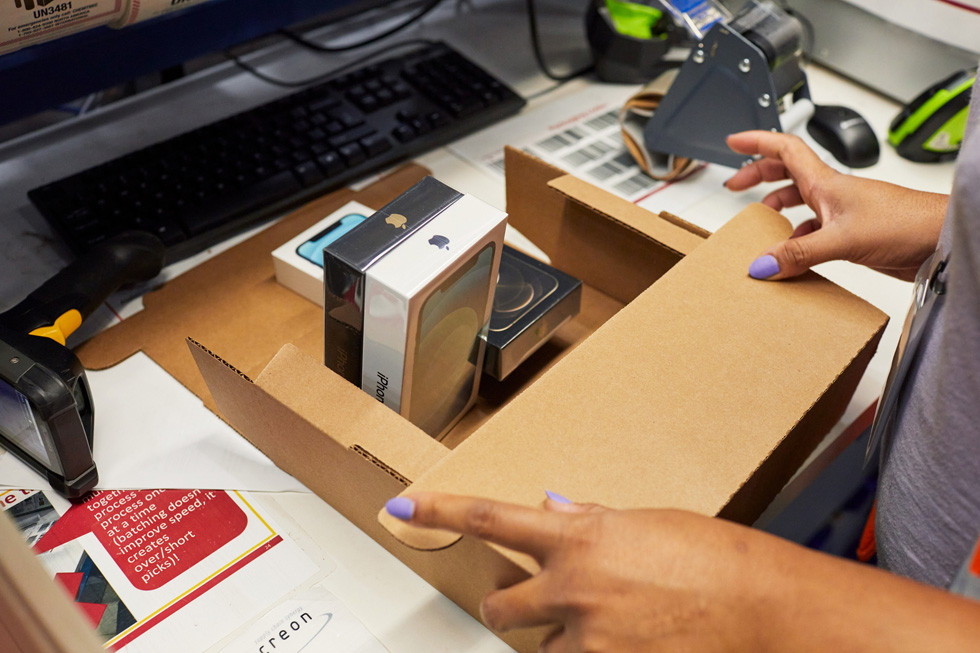 An Apple distribution center employee packs a shipment of iPhone 12 and iPhone 12 Pro. 