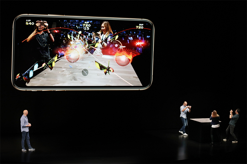 Atli Mar Sveinsson demos Galaga AR on stage with three players.