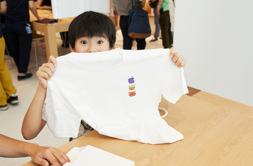 Customer at Apple Kyoto holding up a commemorative t-shirt.