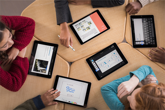 A table of young students using iPads.