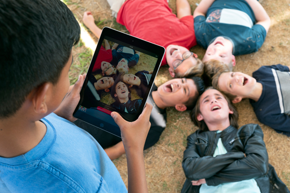 Student uses an iPad to take a photo of classmates.