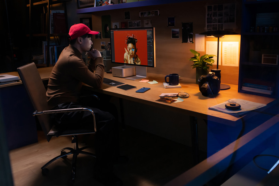 A creative professional works with Mac Studio and Studio Display in an office setting.