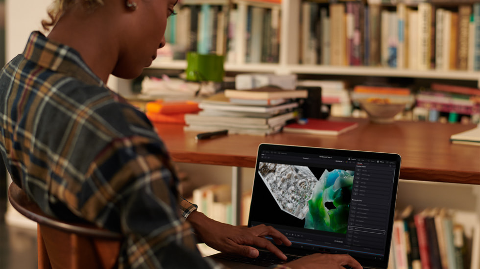 A person uses MacBook Pro in a library setting.