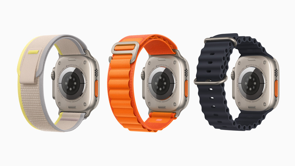 Rückansicht von drei Apple Watch Ultra Modellen mit drei unterschiedlichen Armbändern, mit dem Trail Loop in Grau und Gelb, dem Alpine Loop in Orange und dem Ocean Armband in Schwarz 
