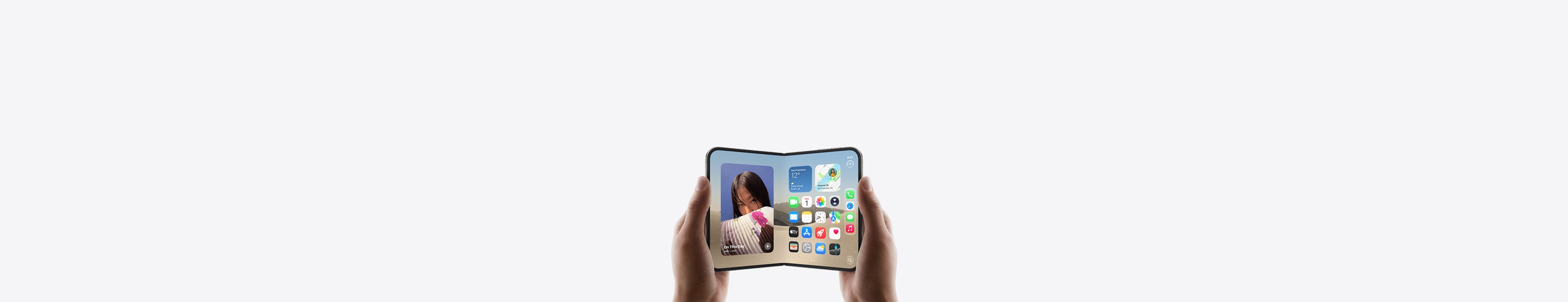 Dve ruky držia iPhone Duo v orientácii na šírku, telefón je roztvorený a na vnútornom displeji sa zobrazuje plocha