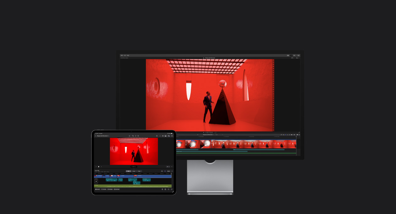 Mac Studio Display, 13 inç iPad Pro, Final Cut Pro zaman çizelgesi, soyut şekilli pencerelere sahip kırmızı bir odada piramit şeklindeki siyah bir yapının uç noktasına gümüş rengi bir top yerleştiren mavi takım elbiseli bir adam