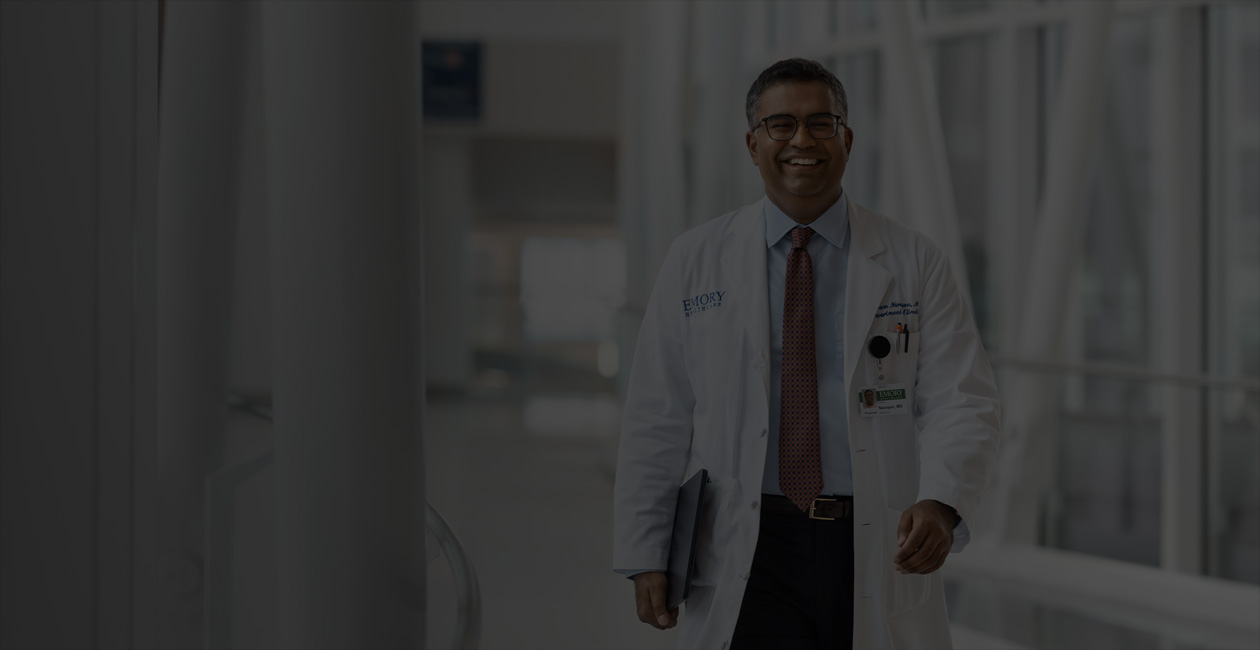 A doctor holding MacBook under their right arm while walking.