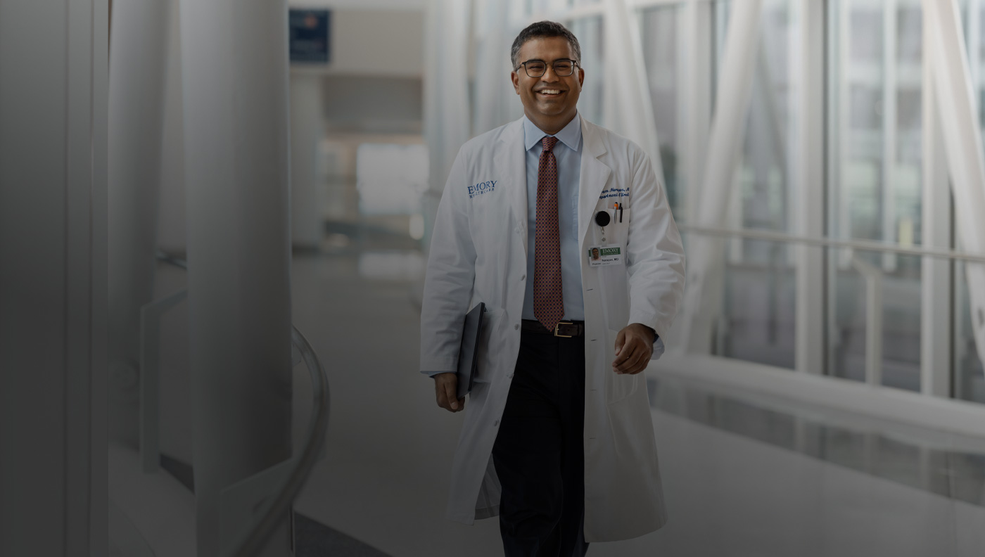 A doctor holding MacBook under their right arm while walking.