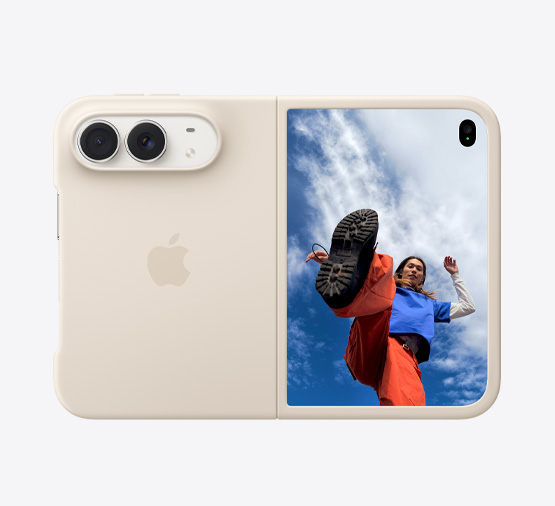 星光白色 iPhone Duo 裝在沙色矽膠保護殼中，呈橫向完全展開的狀態，左上方為雙融合相機；保護殼覆蓋機身背面和正面螢幕的外緣；右側的外螢幕顯示人物站在滿佈雲朵的藍天之下