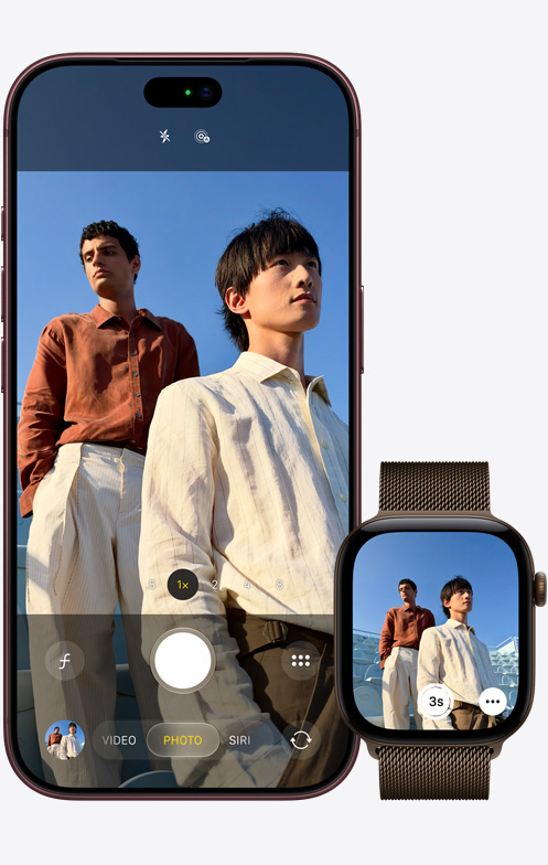 iPhone 18 Pro, вид спереду, камера використовується для зйомки двох чоловіків на фоні блакитного неба, поруч Apple Watch Ultra 3 із відкритим додатком «Дистанційне керування камерою»