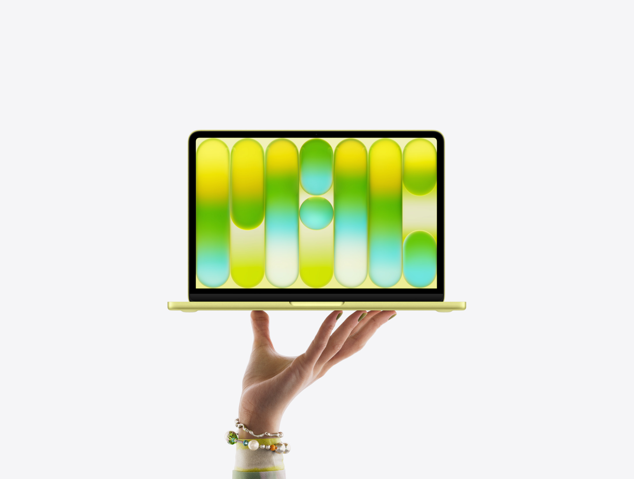 Bir elin parmak uçları üzerinde dengede duran, ekranında renkli, soyut bir desenin gösterildiği puslu sarı renk MacBook Neo